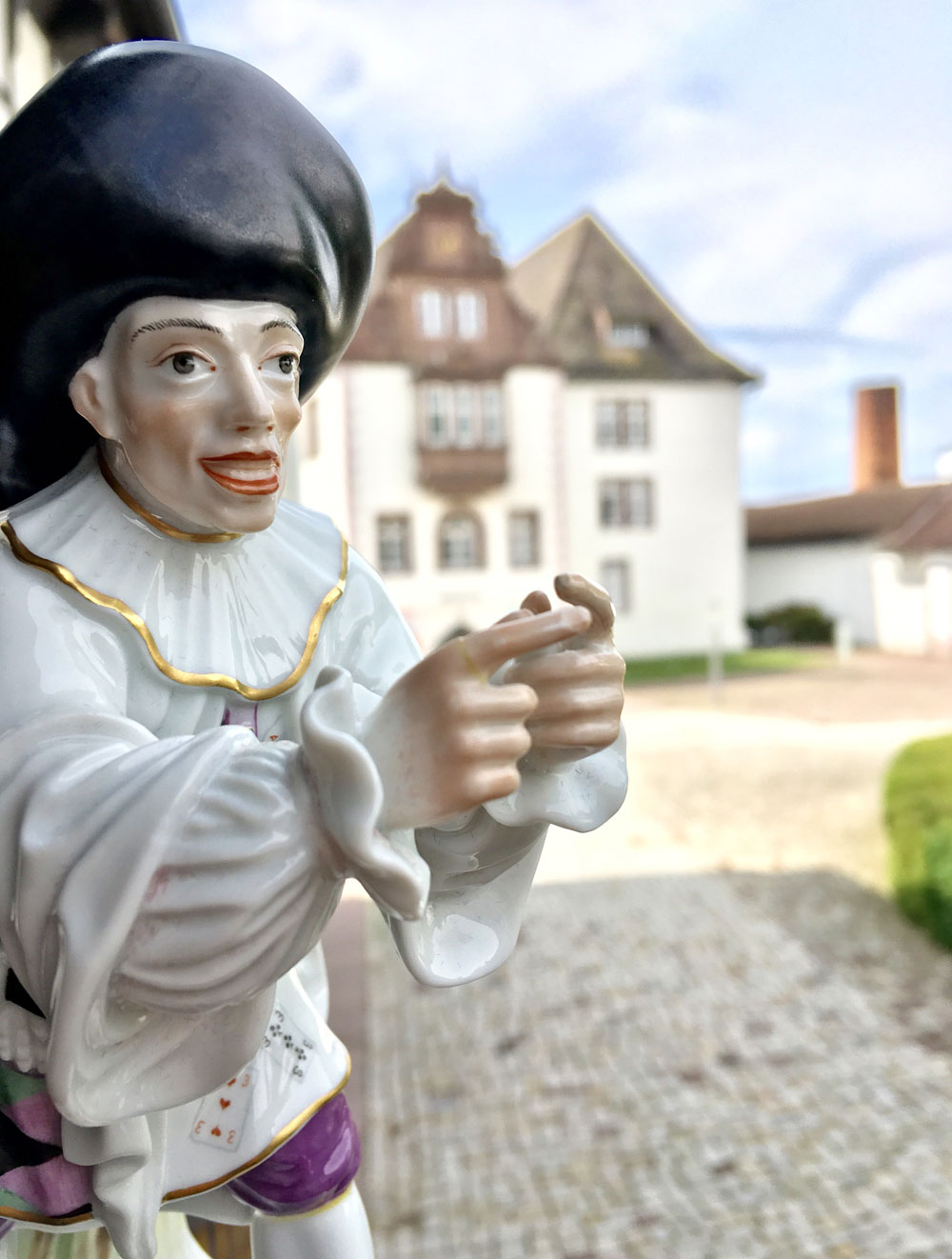 Porzellanfigur, im Hintergrund das Schloss FÜRSTENBERG