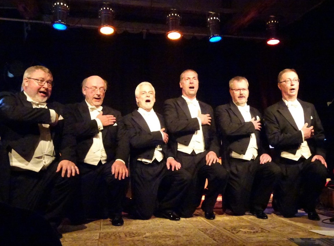 Chor aus mehreren Männern in schwarzen Anzügen