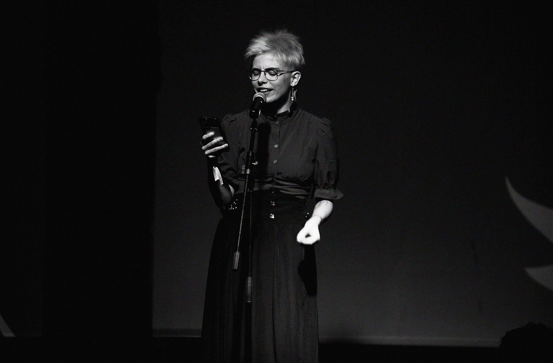 Eine Frau in schwarzen Sachen gekleidet liest auf der Bühne